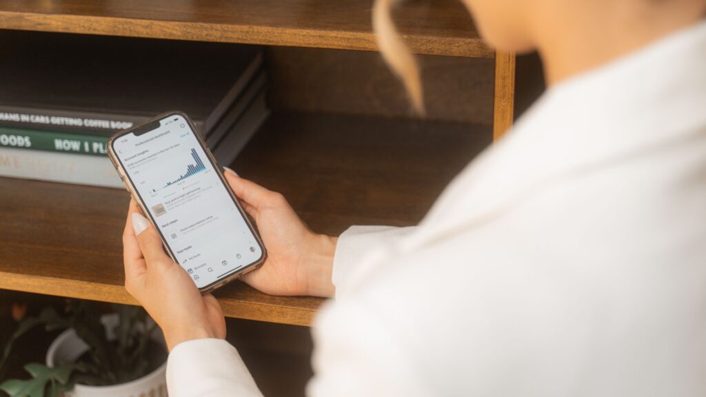 A photo looking over Millie's shoulder at her phone, where she's checking her reach on Instagram.